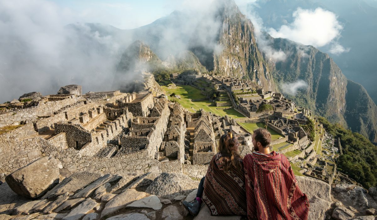 Couple dressed in ponchos watching the ruins of Machu Picchu